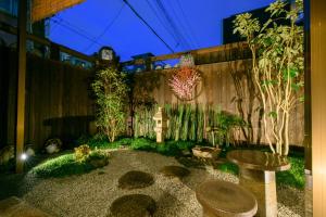 einen Garten in der Nacht mit einer Uhr auf einem Zaun in der Unterkunft Kyooyado Muromachi in Kyoto