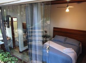 a bedroom with a bed and a glass shower at Pousada Santa Vila in Serra do Cipo
