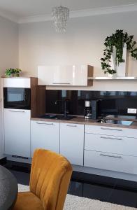 a kitchen with white cabinets and a chair at Bismarck-Apartment in Kaiserslautern