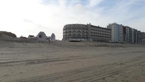 a building on the beach with buildings in the background at Charmant appartement met frontaal zeezicht in Middelkerke