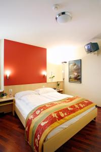 a bedroom with a large bed with a red wall at Hotel De la Paix in Lucerne