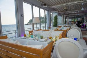 un restaurant avec des tables et des chaises blanches et l'océan dans l'établissement wonderfull view cap d ail monaco, à Saint-Antoine