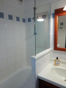 een badkamer met een bad, een wastafel en een spiegel bij LES GRANDS PINS in Carcans