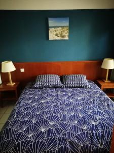 een slaapkamer met een bed met een blauw en wit dekbed bij LES GRANDS PINS in Carcans