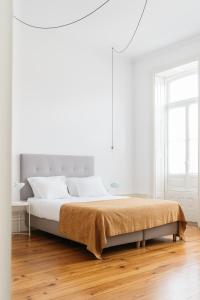 a white bedroom with a large bed and a wooden floor at O da Joana in Porto