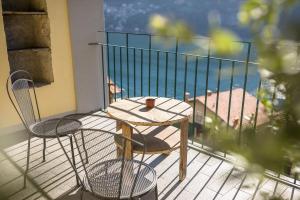 una mesa y sillas en un balcón con vistas al océano en Albergo Diffuso Ca' Spiga, en Laglio