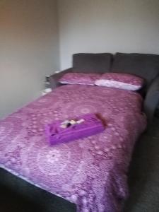 a purple bed with a purple blanket on it at Little Cosy Cwtsh in Pontyclun