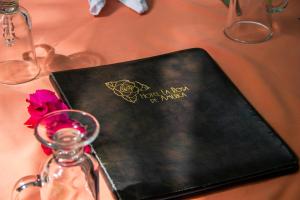 a table with a black book and a bottle and a flower at Hotel La Rosa de America in Alajuela City +117 photos