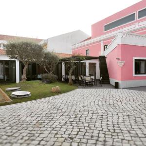 uma entrada de tijolos em frente a um edifício cor-de-rosa em Hotel Acez em Vendas Novas