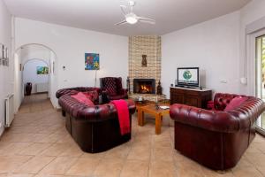 ein Wohnzimmer mit Ledermöbeln und Kamin in der Unterkunft Villa das Palmeiras in Charneca