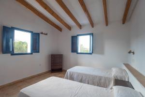 a bedroom with two beds and two windows at CASA PATRICIA Cala Saona in Cala Saona