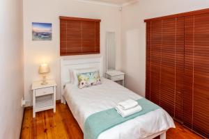 a small bedroom with a white bed and a window at Whale Sea Cottage in Gansbaai