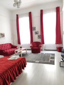 sala de estar con muebles de color rojo y ventanas grandes. en Julia Apartment, en Budapest