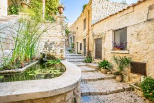 a stone building with a koi pond in a courtyard at Scicli Albergo Diffuso in Scicli