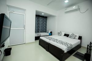 a bedroom with two beds and a flat screen tv at RoaBaa Guesthouse in Batticaloa