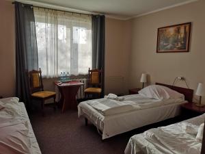 a hotel room with two beds and a table and a window at Hotel Kakadu in Konin