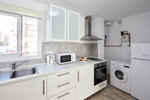 cocina blanca con fregadero y microondas en Sonrisa Apartments, en Benidorm