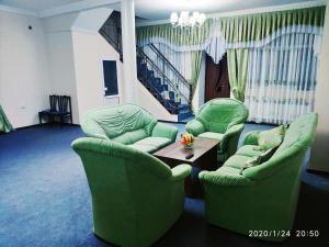 a living room with two green chairs and a table at HOTEL APOLLON in Samarkand