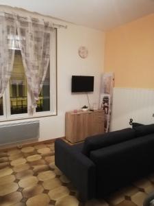 Una sala de estar con un sofá y un televisor de pantalla plana. en LA ROSIERE, en La Fère