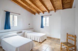 a white room with two beds and a chair at CASA EUGENIO Cala Saona in Cala Saona +7 photos