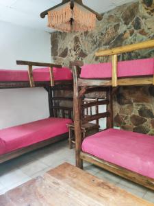 Habitación con literas de madera en una pared de piedra. en Club Hostel Jujuy en San Salvador de Jujuy