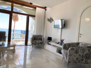 - un salon avec une télévision, une table et des chaises dans l'établissement Pissouri Beach Front Apartments, à Pissoúri