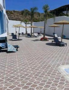 a patio with chairs and umbrellas on a beach at Appartement hôtel cabo dream in Cabo Negro