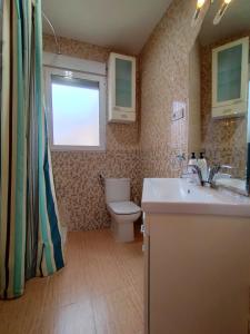 a bathroom with a toilet and a sink and a window at Cabañal Port Marina in Valencia