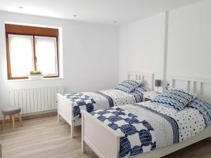 two beds with blue and white comforters in a bedroom at Kaltzada Etxea- Busturia in Axpe de Busturia