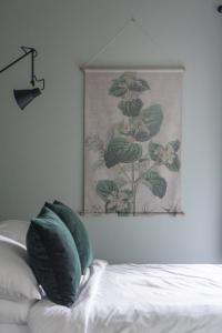 uma pintura na parede acima de uma cama com almofadas verdes em Kilnside em Uplyme
