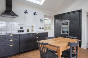 a kitchen with black cabinets and a wooden table at Kilnside in Uplyme