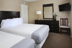 Habitación de hotel con 2 camas y espejo en Aquarius Oceanfront Inn, en Wildwood