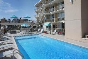 a pool with chairs and umbrellas next to a building at Aquarius Oceanfront Inn in Wildwood