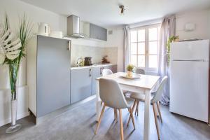 Il comprend une cuisine équipée d'une table et d'un réfrigérateur blanc. dans l'établissement Maison cosy et paisible au coeur de Beauvais, à Beauvais