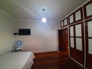 um quarto com uma cama, uma ventoinha e uma televisão em Casa da Tuca em São João del Rei