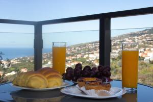 two plates of food on a table with two glasses of orange juice at Amoreira House in Calheta