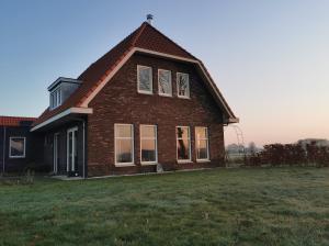 una casa de ladrillo con techo de gambrel en un campo en Bed & Breakfast de Vink en Terschuur