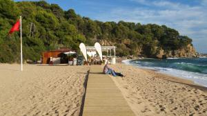 Eine Frau, die auf einer Promenade am Strand sitzt. in der Unterkunft Villa Zen Costa Brava in Lloret de Mar