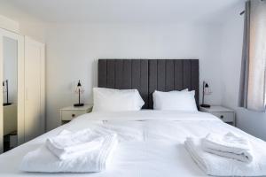 um quarto com uma cama branca com duas toalhas em Suites by Rehoboth - Abbey Wood Station - London Zone 4 em Londres