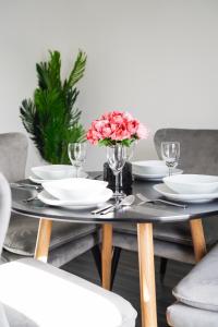 uma mesa de jantar com pratos e flores em Suites by Rehoboth - Abbey Wood Station - London Zone 4 em Londres
