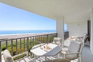 Cape Winds في كيب كانافيرال: شرفة مع طاولة وكراسي والشاطئ