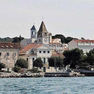 un grand bâtiment avec une tour d'horloge au sommet d'une ville dans l'établissement Apartment Dukic, à Sveti Filip i Jakov