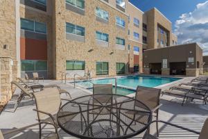um pátio com uma mesa e cadeiras ao lado de uma piscina em Holiday Inn Express & Suites - San Marcos South, an IHG Hotel em San Marcos