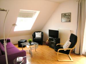 una sala de estar con un sofá púrpura y sillas en Strandblick, en Horumersiel