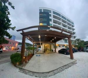 a building with a pavilion in front of a parking lot at Hotel e Pousada Manguinho in Penha