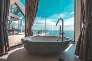 uma banheira num quarto com uma grande janela em Sky Dream Villa Award Winning Sea View Villa em Chaweng Noi Beach