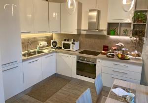 a kitchen with white cabinets and a sink and a table at B&B Nearby Malpensa in Samarate