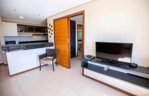 Manacá Apartamentos , Kariri Beach , Cumbuco في كومبوكو: غرفة معيشة فيها تلفزيون ومطبخ