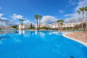 a large swimming pool with palm trees and buildings at Beautiful Seaside Apartments in Tavira