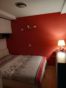 a bedroom with a bed and a red wall at Brand New Apt in City Center in Bitola